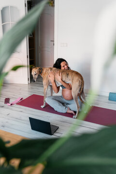 Pregnant woman hugging her dog at home