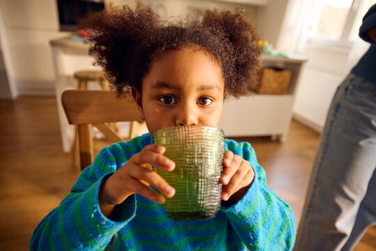 Little girl drinks water at home