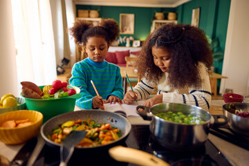 Little girls scribbling away in the kitchen