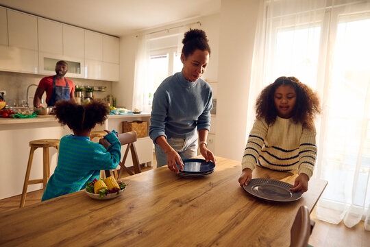Mom and daughter serve plates on the table