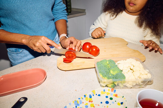 Woman chops red tomatoes on the countertop