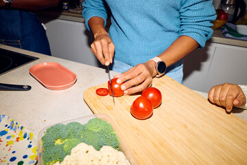 Woman chops red tomatoes on the countertop