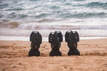 Seascooter stands on the sandy beach by the ocean. Seascooter is ready for underwater adventure and diving. Seascooter shows modern design for marine use. Seascooter waits as waves move behind it.