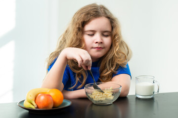 Balanced meal with milk. Kid eating breakfast meal. Child eating in kitchen space. Healthy breakfast with milk. Smiling face at breakfast. Child enjoying cereal at table. Morning breakfast in kitchen.