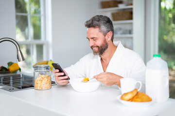 Mature Man eat breakfast in kitchen with fresh cereal and milk. Man eats healthy lunch enjoys a nutritious salad and vegetables at home. Tasty snack at kitchen table. Nutritious meal healthy food.