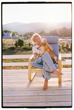 Woman sitting with her Shiba Inu dog on the porch of her house 