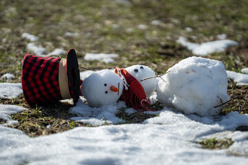 Spring warm weather. End of winter, hello spring. Winter snowman disappearing in early spring. Winter and spring seasons change.