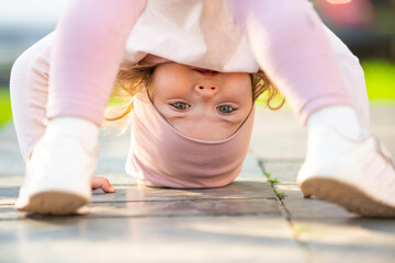 Funny child face upside down. Crazy toddler upside down. Child balance upside down outdoor. Baby activity and child development. Child girl play upside down.