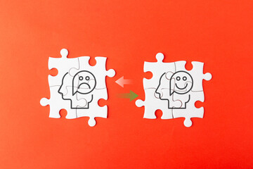 White jigsaw puzzles on a red background showing a transition from a sad face to a happy face, representing mental health recovery, emotional transformation, therapy success, and positive mindset.