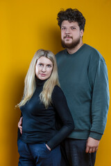 Lifestyle Concepts. Young Caucasian Smiling Happy Adorable Couple As Friendly Family Man And Woman Casual Clothing Together Embracing Cuddle Isolated on Seamless Yellow Background