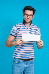Good Looking Happy Smiling Caucasian Handsome Brunet Man With White Empty Plate in Hand Posing in Glasses Gesturing With Finger Against Blue