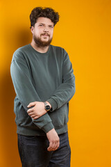 Youth Lifestyle. Caucasian Young Tranquil Brunette Handsome Man in Green Shirt Sweatshirt As Casual Clothes Looking Straight Isolated on Plain Light Yellow Background in Studio.