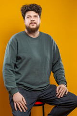 Youth Lifestyle Concepts. Caucasian Young Tranquil Brunette Handsome Man in Green Shirt Sweatshirt As Casual Clothes Looking Straight Isolated Over Light Yellow Background