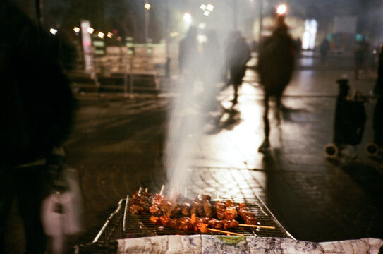 Street Vendor Grilling Skewers at Night 