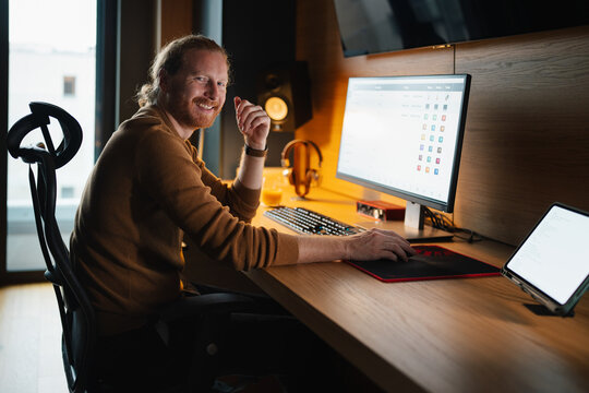 Smiling man working on computer in modern office space
