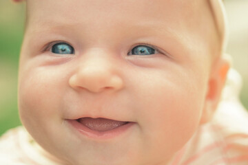 Smiling baby portrait lose up. Cute baby face with blue eyes. Happy baby. Newborn baby portrait.