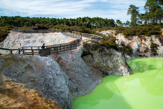 Mature lady walking beside green acidic geothermal mineralised water of Devils Bath - Waiotapu
