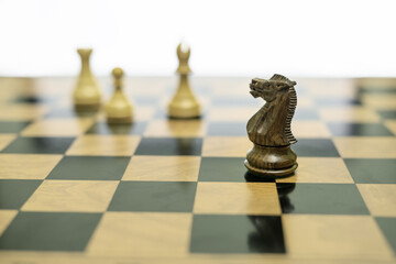Black chess knight placed irregularly on a chessboard with blurred white pieces behind © Visual Voyager