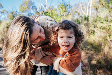 Portrait of happy little girl smiling with mum outdoors