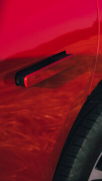 Close-up film-style shot of a red car&rsquo;s retractable door handle 