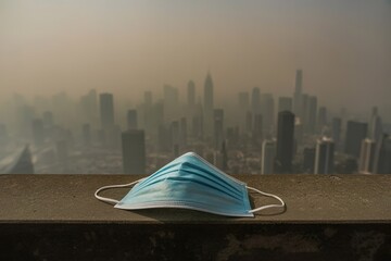 discarded face mask with city skyline in thick smog behind. Urban environment destruction theme