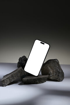 Smartphone with blank screen displayed on natural stone arrangement