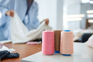 Craftsperson diligently arranging textiles and accessories in brightly lit sewing studio