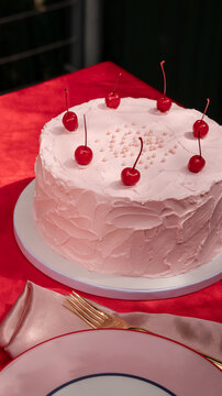 Pink Frosted Cake with Cherries on Red Table