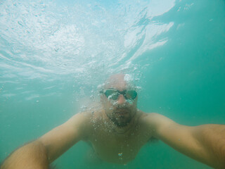 Man swimming underwater with goggles