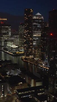 Vertical aerial view of Canary Wharf in London at night. Illuminated financial district located on the Isle of Dogs