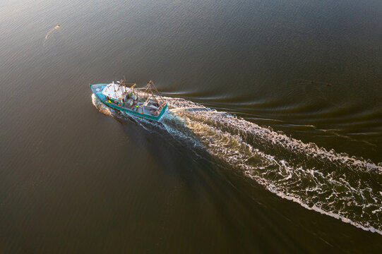 Fishing trawler leaving a wake across still water