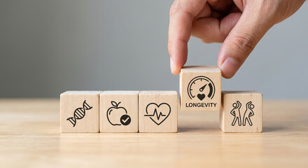 Hand placing wooden 'LONGEVITY' block with DNA, healthy eating, heart health, and aging icons