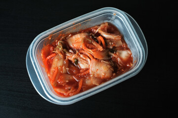 colse up kimchi korean ready to eat in plastic box on black table.