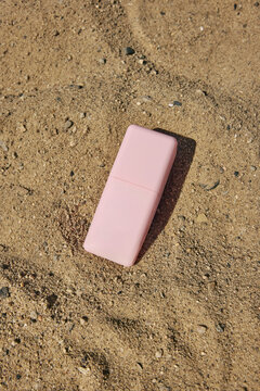 Unlabeled pink cream jar in the sand