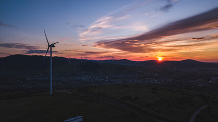 Wind turbines standing on rolling green hills under a dramatic sky 