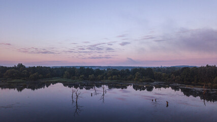 A calm lake at sunrise with mirror-like reflections of the sky 