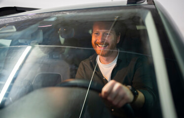 Man smiles while sitting in car during evening drive
