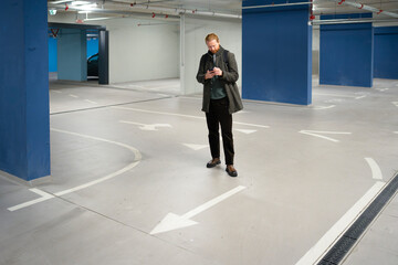 Man looks at phone in empty parking garage
