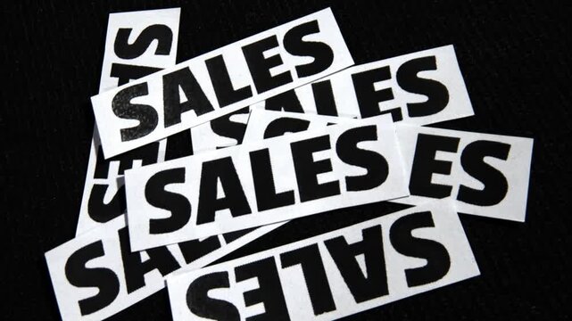 Sales text written on the paper pieces randomly scattered with black backdrop, business concept