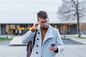 Young businessman checking smartphone in urban winter city