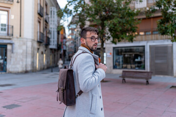 Fototapeta premium Young man walking street with backpack in winter city