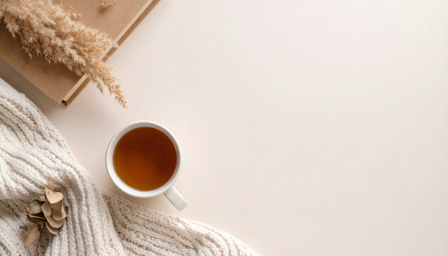 Cozy Flat Lay with Tea Cup, Notebook, and Knitted Sweater on Beige Background