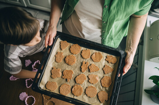 Mother and son baking Christmas cookies in the kitchen at home