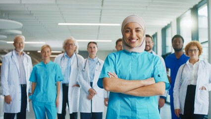 Confident female medical worker standing in corridor. Smiling nurse showing professionalism while leading group of doctors behind her. Preparing for demanding tasks during busy hospital routine.