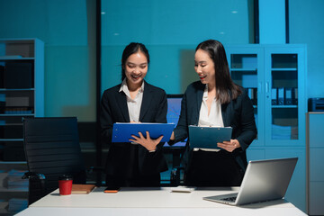 Financial analysts work overtime analyzing data on tablets, laptops, and graphs. Collaboration, teamwork, and planning.