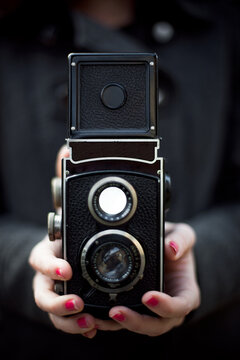 Close up of hand holding vintage twin lens reflex camera with nail polish