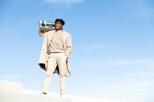 Person with boombox in trench coat enjoys music outdoors in Barcelona