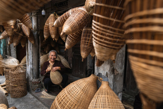 Artisan weaving bamboo fish trap outdoors in Hanoi Vietnam