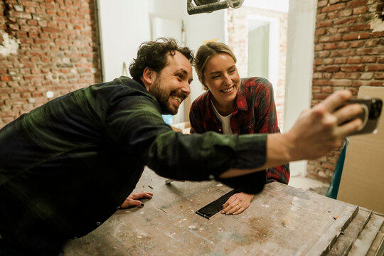 Smiling couple taking selfie at construction site during home renovation