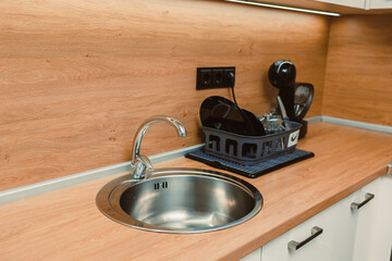 Kitchen sink with clean dishes on a drying rack, taken in a modern kitchen space during daylight...